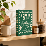 Grünes Deko Buch Coffee Club auf Sideboard